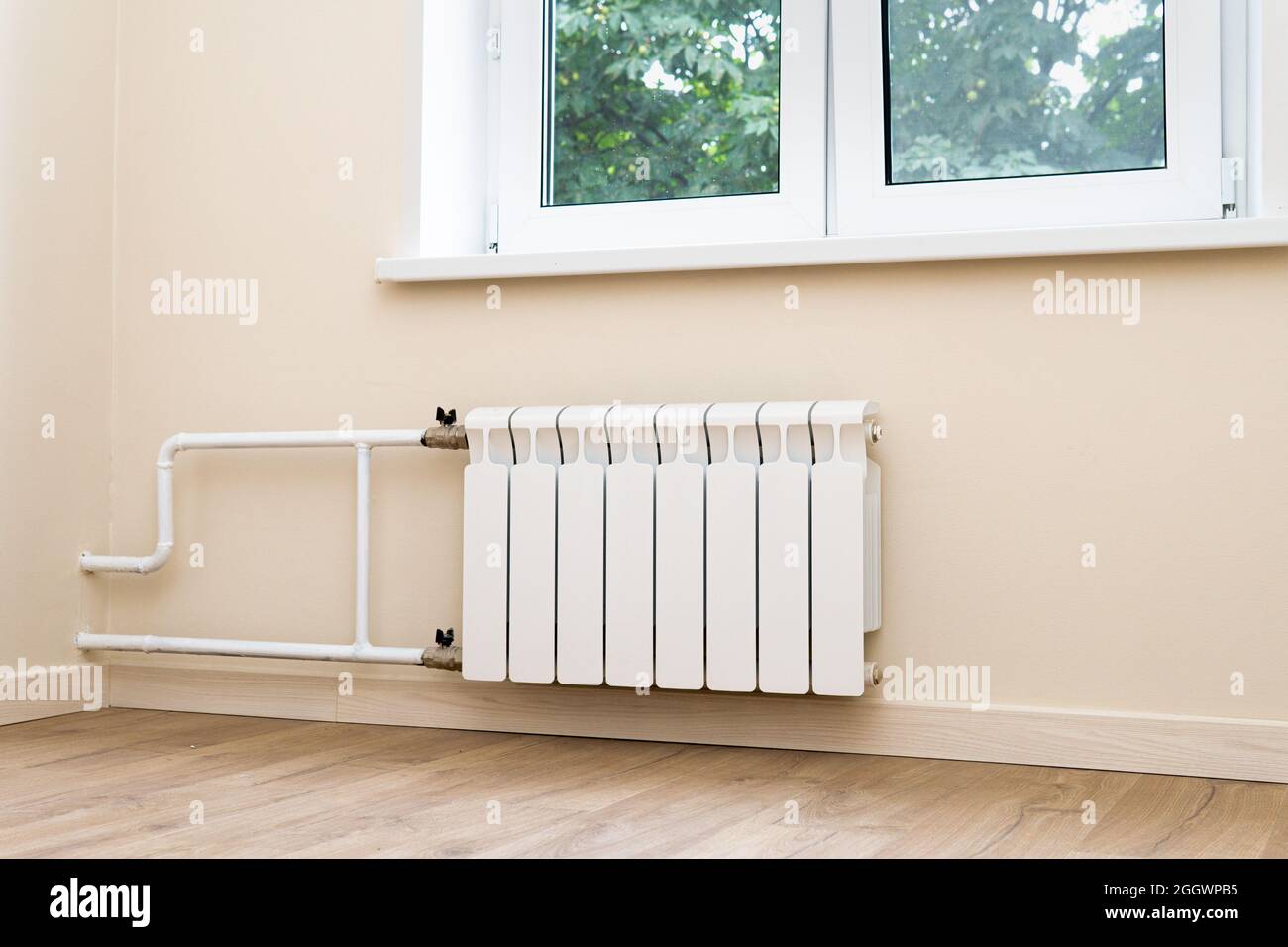 Moderno radiador de calefacción central de agua conectado a la pared bajo  la ventana del apartamento Fotografía de stock - Alamy