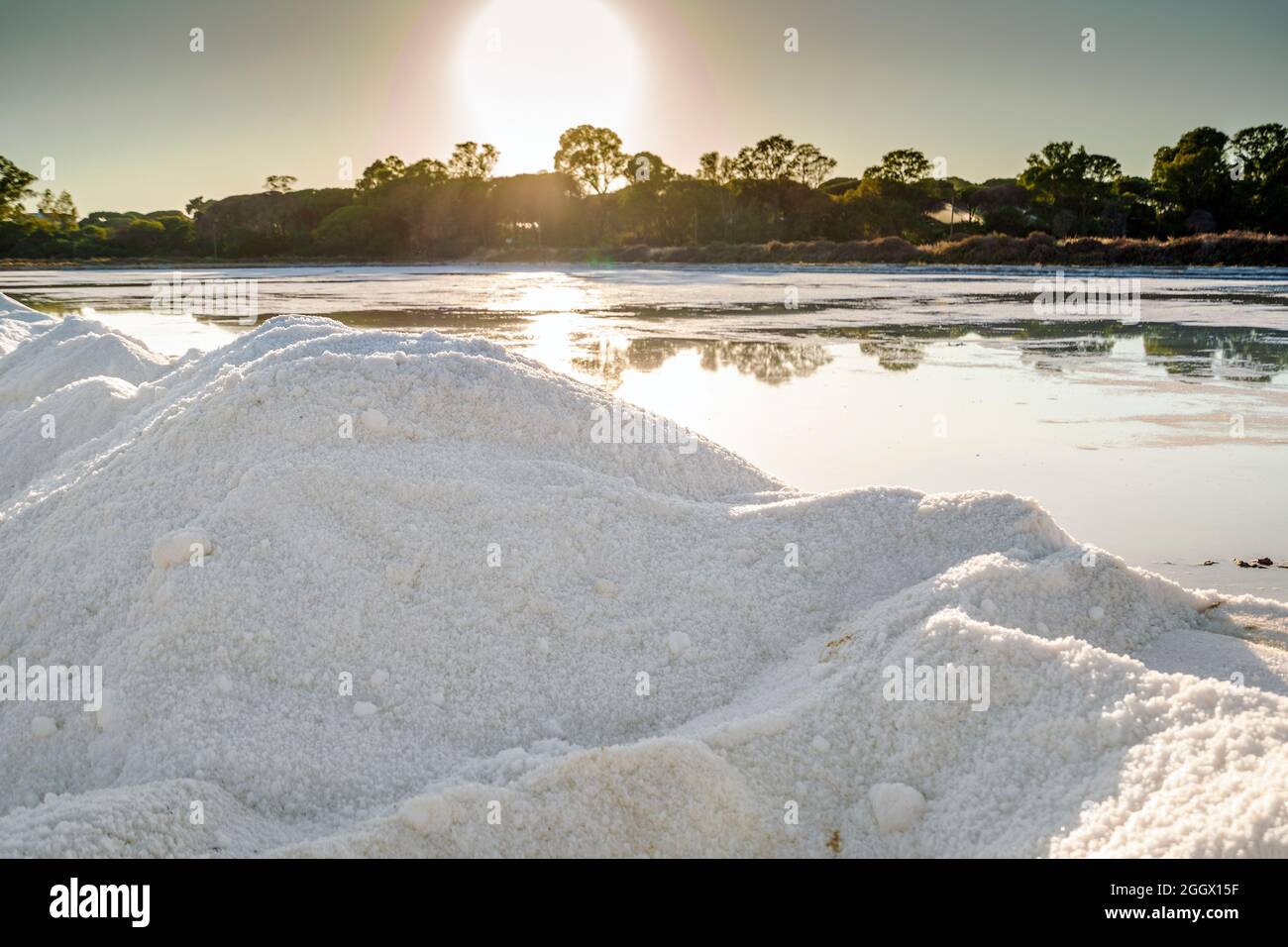 Un montón de cristales de sal junto a un estanque lleno de sal después de la evaporación del agua del océano en salines en Faro, Algarve, Portugal Foto de stock