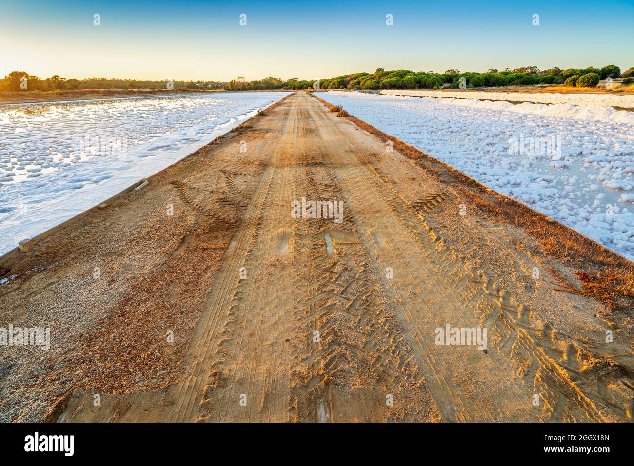Caminos entre dos estanques llenos de sal después de la evaporación del agua del océano en salines en Faro, Algarve, Portugal Foto de stock