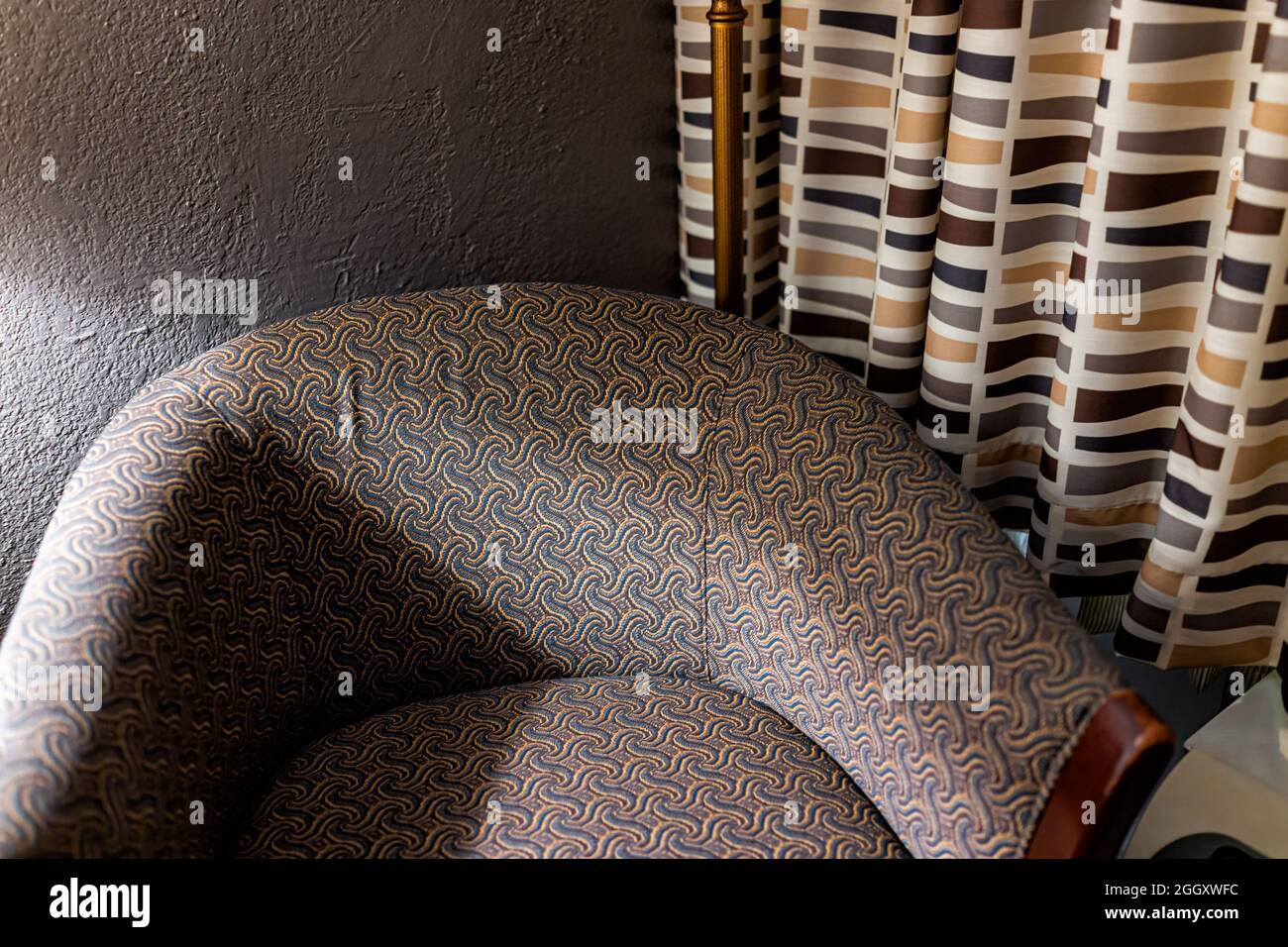 Primer plano de un sillón perezoso con un acento, silla con apoyabrazos por cortinas en la noche oscura con luz de lámpara en el interior de la casa Foto de stock