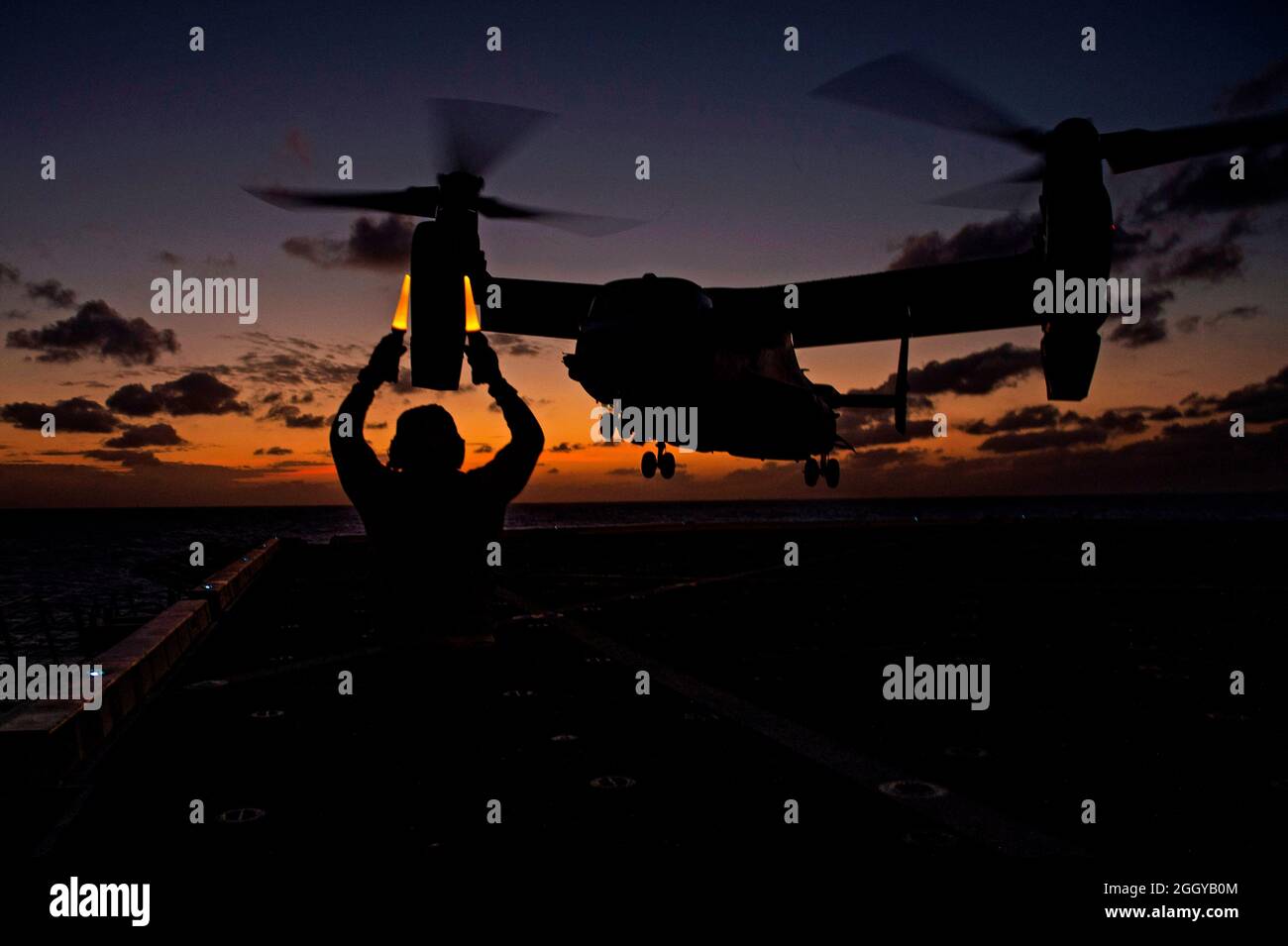 MAR FILIPINAS (18 de marzo de 2020) – Aviation Boatswain's Mate (Handling) 3rd Class Deon Sanders, del Bronx, N.Y., asignado al buque de transporte anfibio USS Green Bay (LPD 20), clase San Antonio, señala a un MV-22 Osprey asignado al buque de asalto anfibio USS America (LHA 6) cuando se despida de la cubierta de vuelo. Green Bay, parte del equipo de la Unidad Expedicionaria Marina del Grupo de Huelga Expedicionaria de América 31st, está operando en el área de operaciones de la Flota de Estados Unidos 7th para mejorar la interoperabilidad con aliados y socios y servir como una fuerza de respuesta lista para defender la paz y la estabilidad en la región del Indo-Pacífico Foto de stock