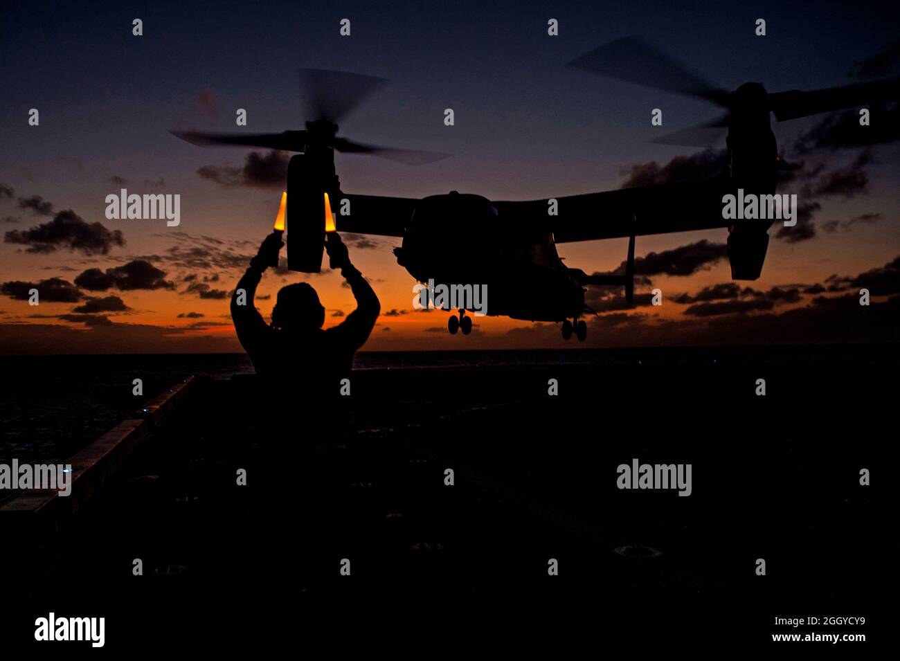 PHILIPPINE SEA (18 de marzo de 2020) Aviation Boatswain's Mate (Handling) 3rd Class Deon Sanders, de Nueva York., asignado al buque portuario de transporte anfibio USS Green Bay (LPD 20), señala un MV-22 Osprey asignado al buque anfibio de asalto USS America (LHA 6) cuando se despida de la plataforma de vuelo. Green Bay, parte del Grupo de Huelga Expedicionaria de América y del equipo de la Unidad Expedicionaria Marina 31st, está operando en el área de operaciones de la Flota 7th de Estados Unidos para mejorar la interoperabilidad con aliados y socios y servir como una fuerza de respuesta lista para defender la paz y la estabilidad en el Indo- Foto de stock