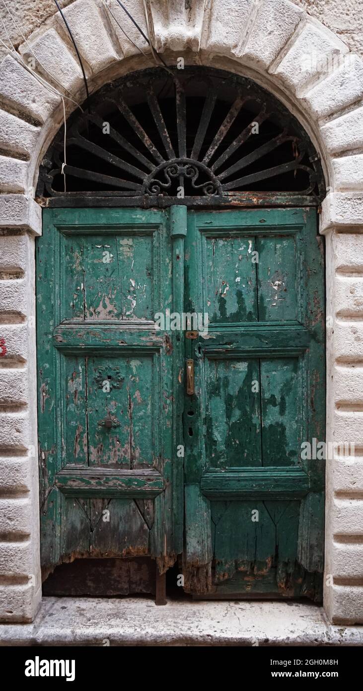 Una vieja puerta verde de madera con un dosel de metal sobre ella, en Kotor, Montenegro Foto de stock