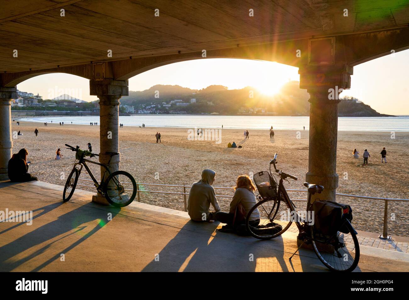 Pareja con sus bicicletas, Puesta de sol en la playa de La Concha, joya de Donostiarra por excelencia, emblema de la ciudad, incomparable entorno, Se encuentra en Foto de stock