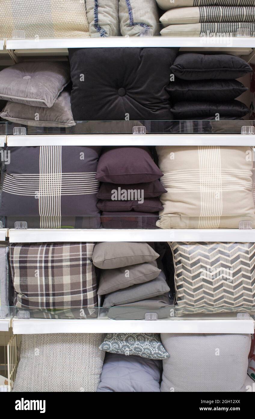 Cojines de escala gris frío y ropa de cama en estantes. Enfoque selectivo. Foto de stock