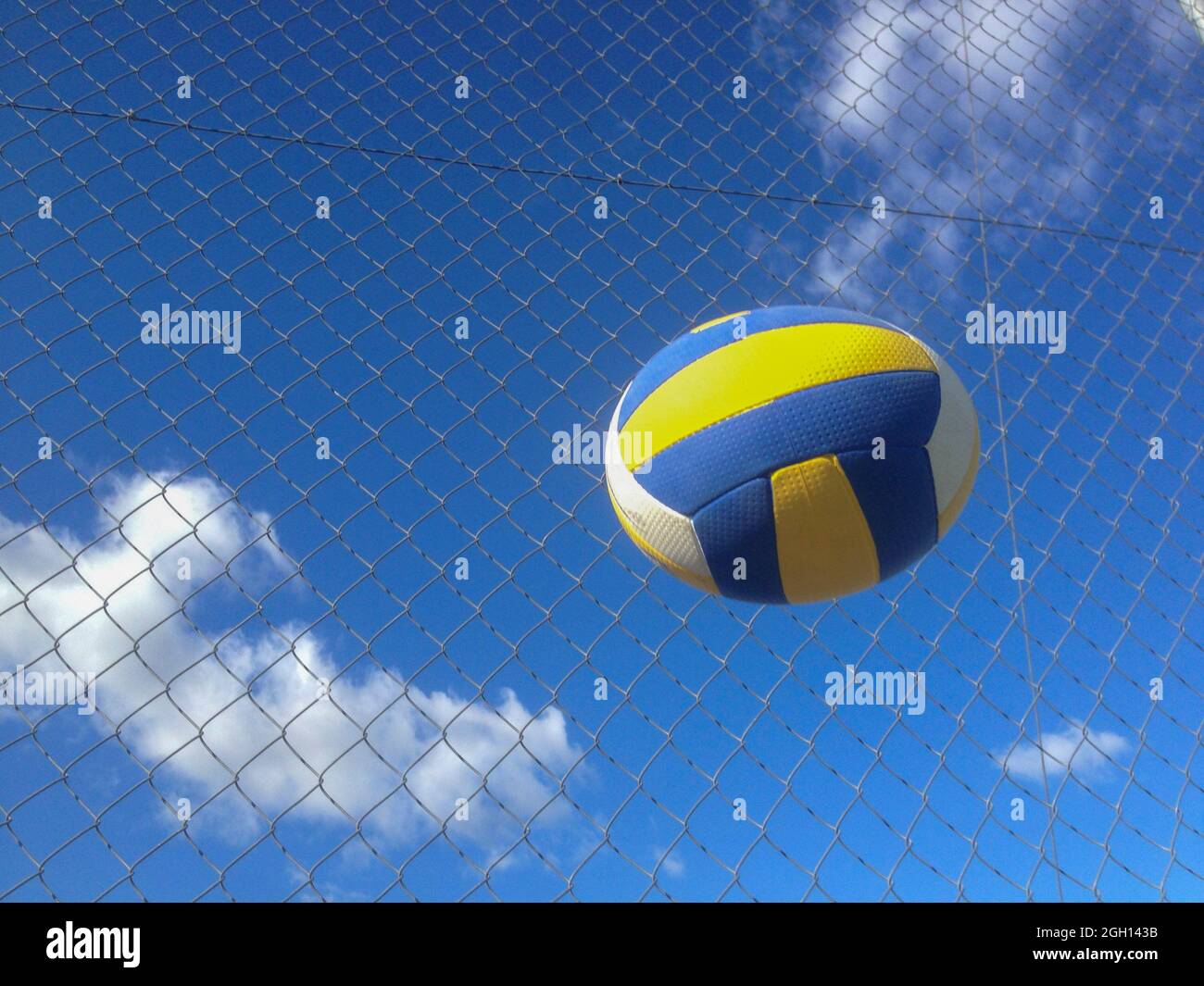 Pelota de voleibol en el aire sobre el fondo de la cerca de alambre. Objeto de movimiento deformado. Foto de stock