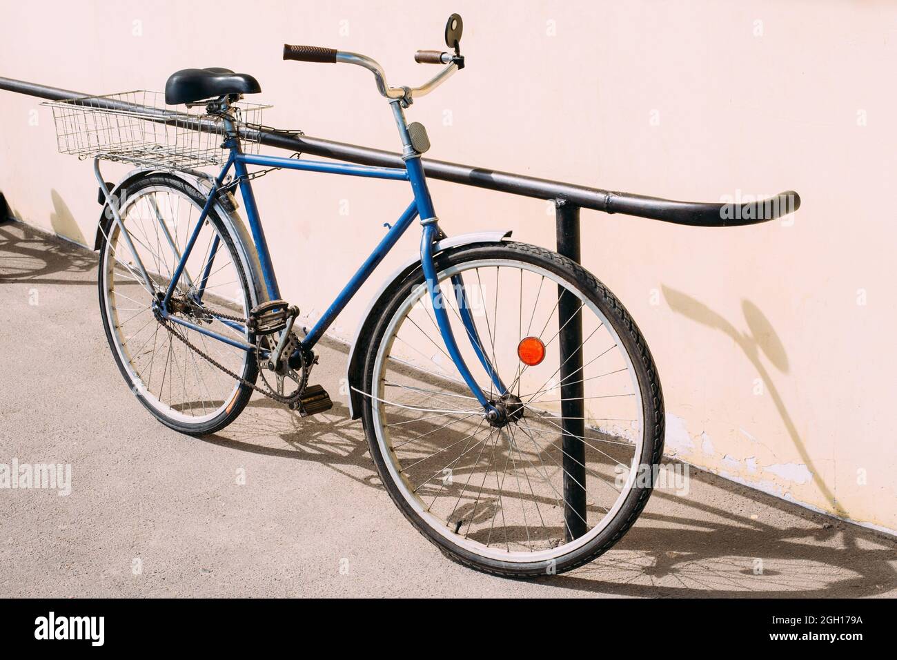 Rareza antigua Bicicleta Azul aparcado junto a la pared amarilla. Foto de stock