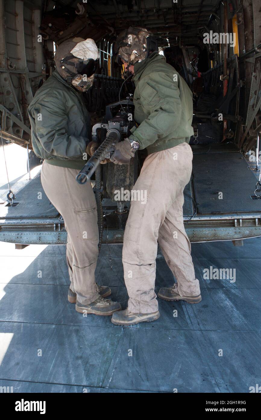 U.S. Marines Cpl. Zachary Hughes (izquierda) y Lance Cpl. Madison DeLoach, jefes de tripulación, Marine Heavy Helicopter Squadron 363 (HMH-363), quite una ametralladora de aviones calibre .50 para cargar equipo en un helicóptero de estallones marinos CH-53D, Camp Bastion, Helmand Province, Afganistán, 5 de enero, 2012. HMH-363 realizó operaciones de vuelo en apoyo de tropas en toda la provincia de Helmand. Foto de stock
