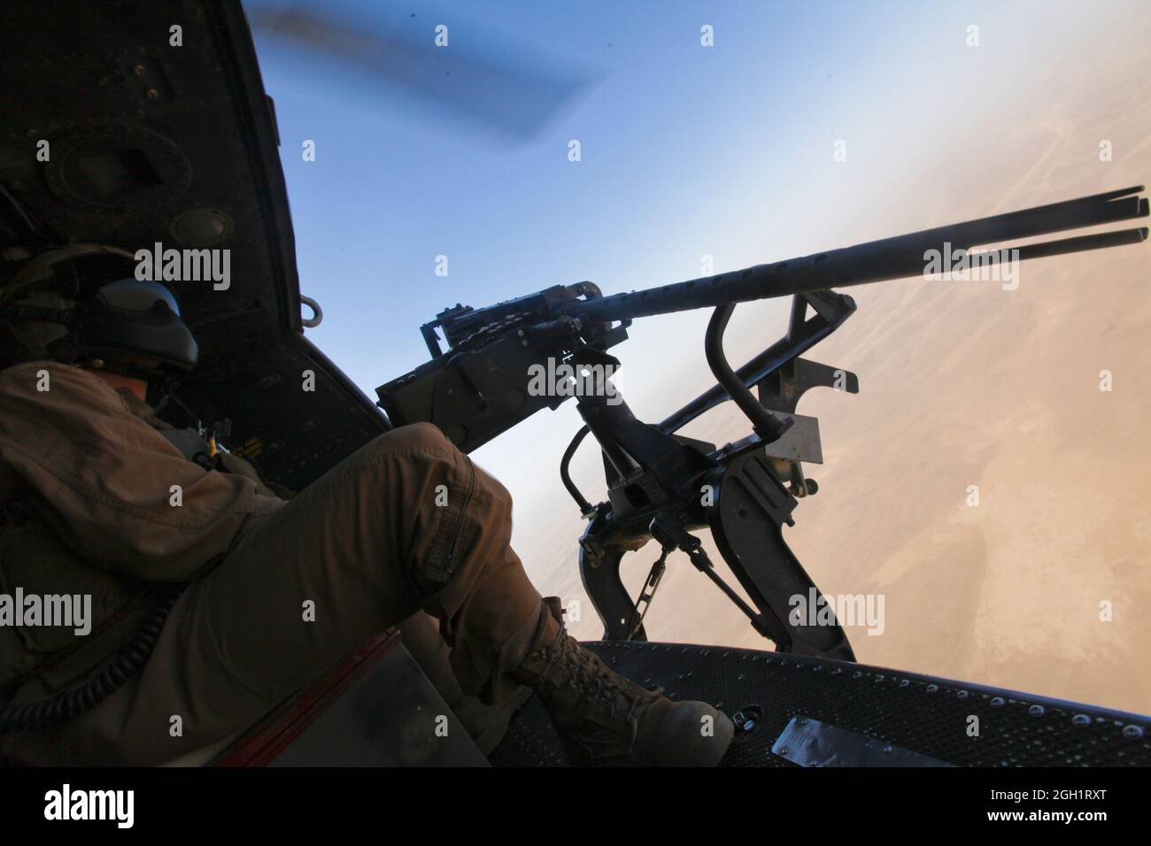 CPL. Carson Ferraro, un jefe de la tripulación Huey UH-1Y con el Escuadrón de Helicópteros Marine Light Attack 369, 3rd Marine Aircraft Wing (delantero), manan una pistola de puerta de calibre .50 mientras volan una misión de reconocimiento aéreo en apoyo del Batallón 3rd, División Marina 1st, septiembre de 3. Ferraro y su tripulación visitaron un campo de tiro después de la misión para practicar el disparo de los sistemas de armas del helo. Foto de stock