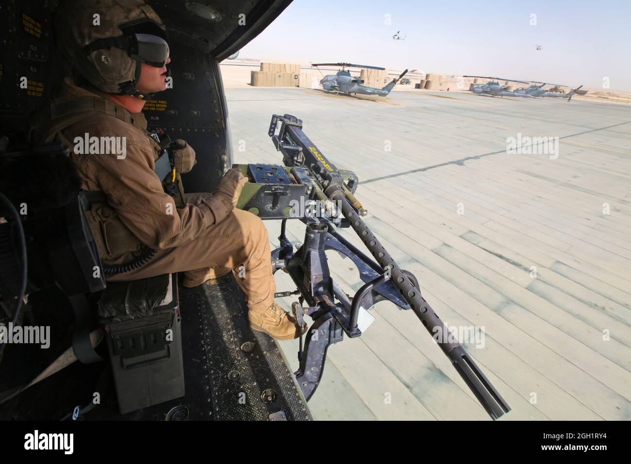 CPL. Carson Ferraro, un jefe de la tripulación Huey UH-1Y con el Escuadrón de Helicópteros Marine Light Attack 369, 3rd Marine Aircraft Wing (Adelante), habla con sus pilotos a través del aterrizaje en el campo aéreo aquí después de realizar una misión de reconocimiento aéreo el 3 de septiembre, en apoyo del Batallón 3rd, División Marina 1st. Ferraro y su tripulación tomaron fotografías de varios lugares para ayudar a familiarizar a los infantes de marina de tierra con el área en la que operarán. Foto de stock