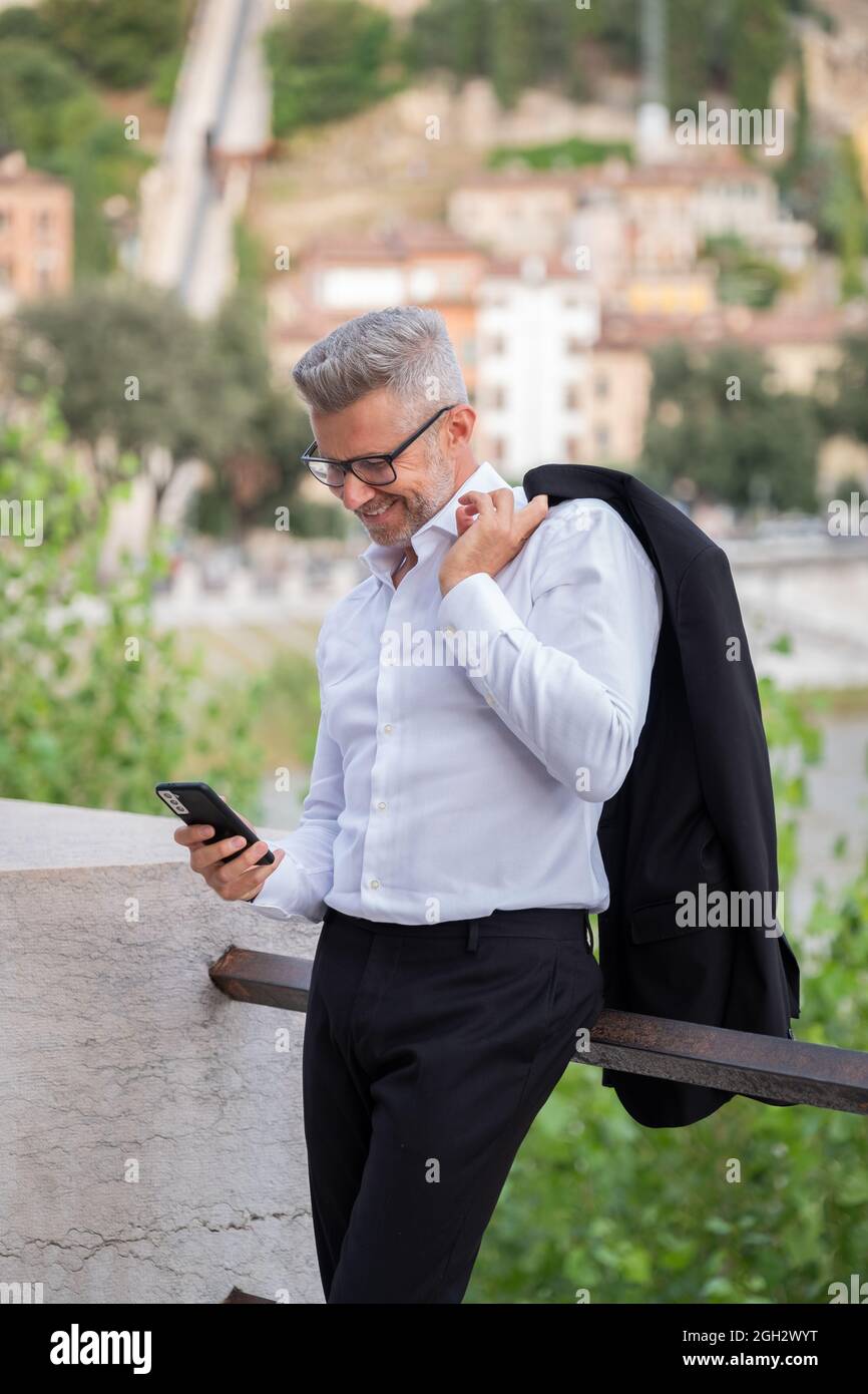Hombre de negocios haciendo una llamada de videoconferencia en un smartphone y hablando en la calle, mirando la pantalla. Feliz hombre haciendo selfie con el teléfono móvil al aire libre Foto de stock
