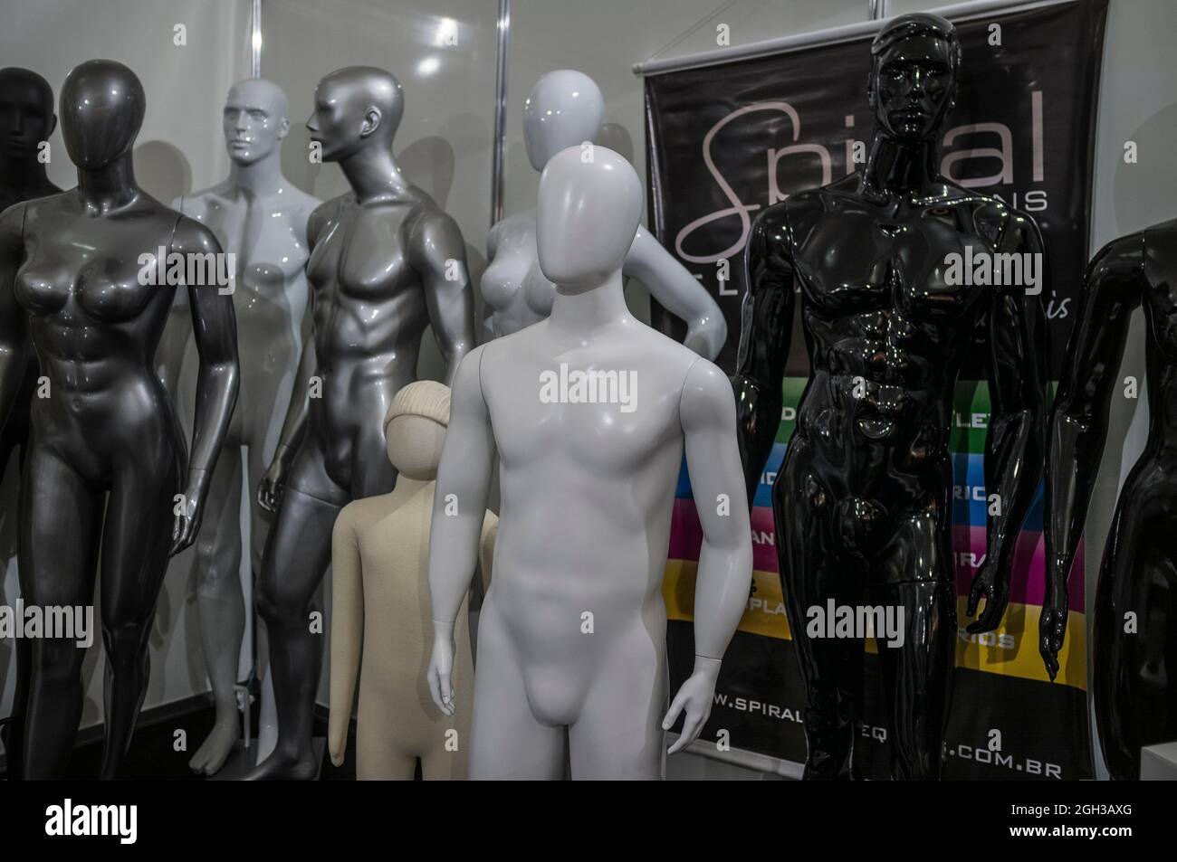 Dummies multiétnico (varios colores), multigénero (formas varios) y multigeneración (varios tamaños) en el almacén de la feria de la moda. Foto de stock