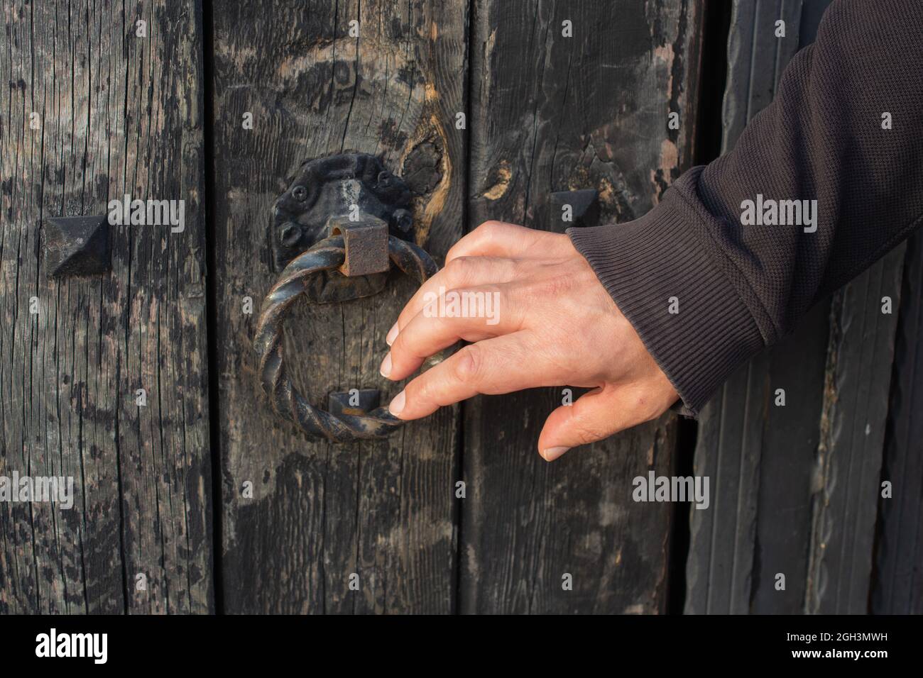 un primer plano de la mano de un hombre que llama a una vieja puerta de  madera Fotografía de stock - Alamy