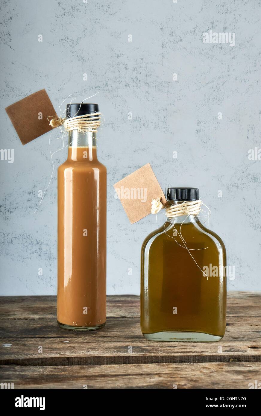 dos botellas de licores artesanales sobre mesa rústica de madera. fondo  gris. horizontal Fotografía de stock - Alamy
