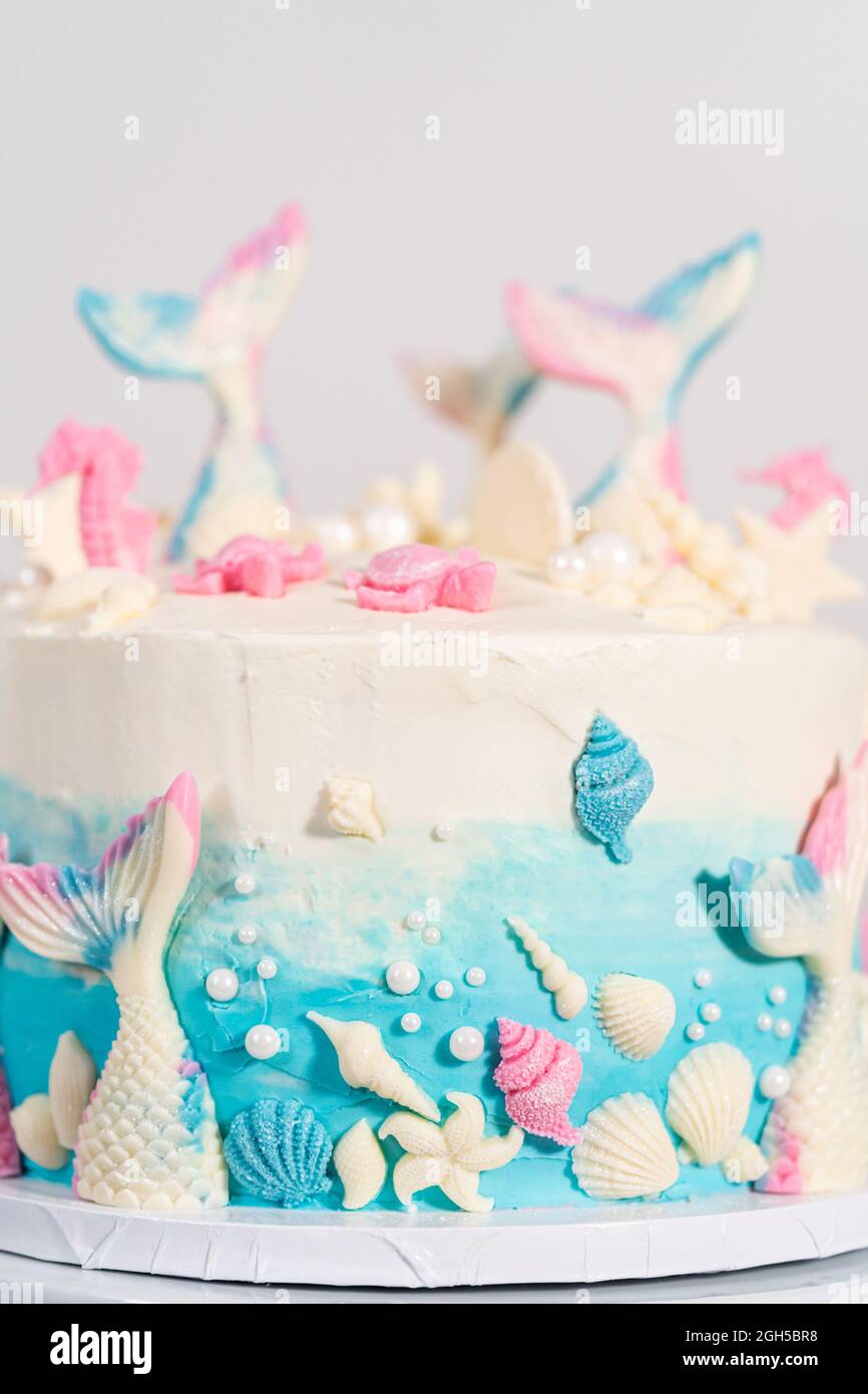 Pastel de vainilla de 3 capas con temática de sirena decorado con colas de  sirena de chocolate y conchas sobre un soporte de pastel blanco Fotografía  de stock - Alamy