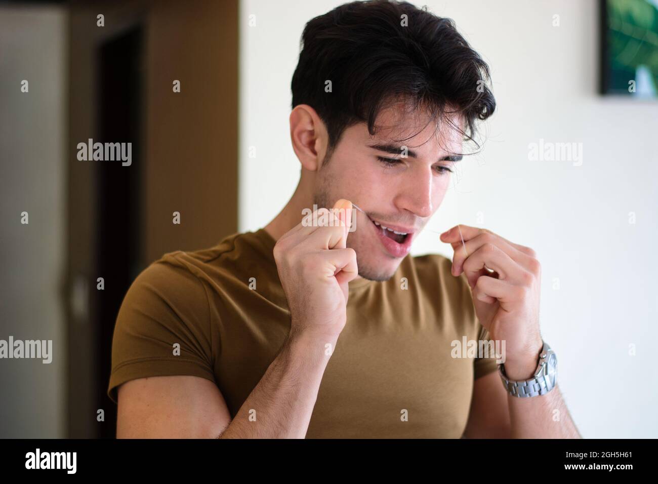 Hombre joven que usa hilo dental para limpiar los dientes Fotografía de  stock - Alamy