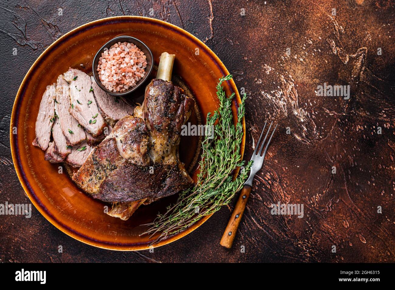 Pierna de cordero asado a la barbacoa cortada en un plato rústico. Fondo  oscuro. Vista superior. Espacio de copia Fotografía de stock - Alamy