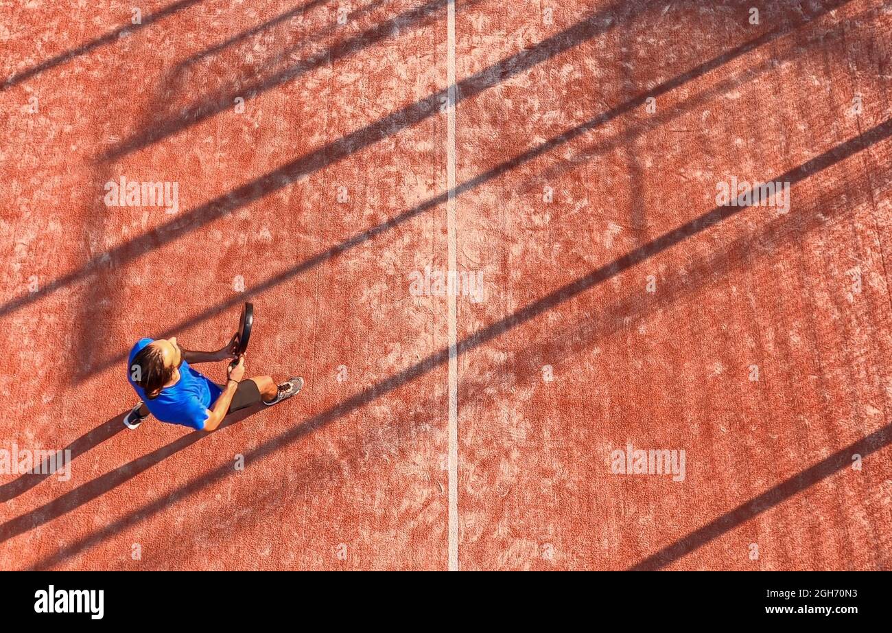 Vista desde arriba de un jugador profesional de pádel que sostiene la raqueta durante un partido en una pista al aire libre. Foto de stock