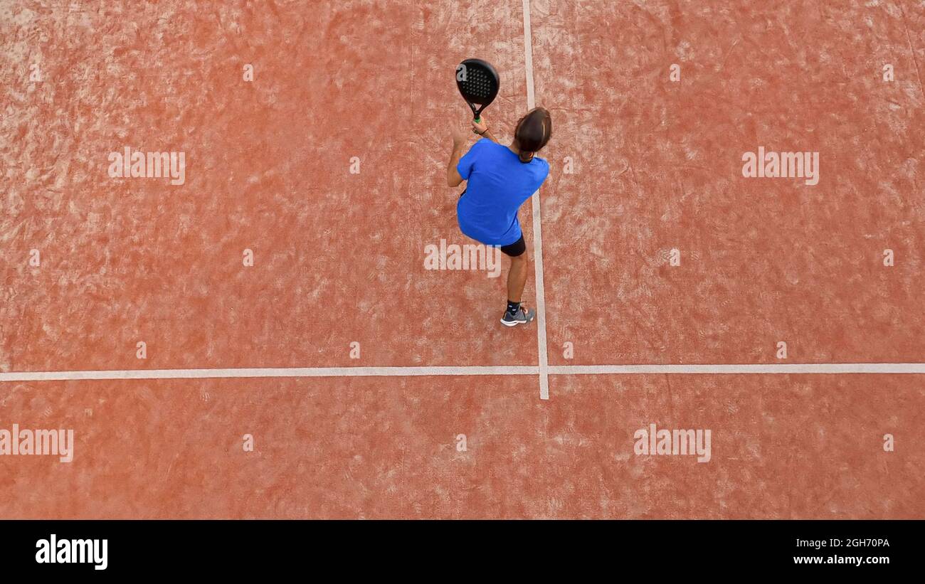 Vista superior de un jugador profesional de pádel que va a golpear el balón durante un partido al aire libre. Foto de stock