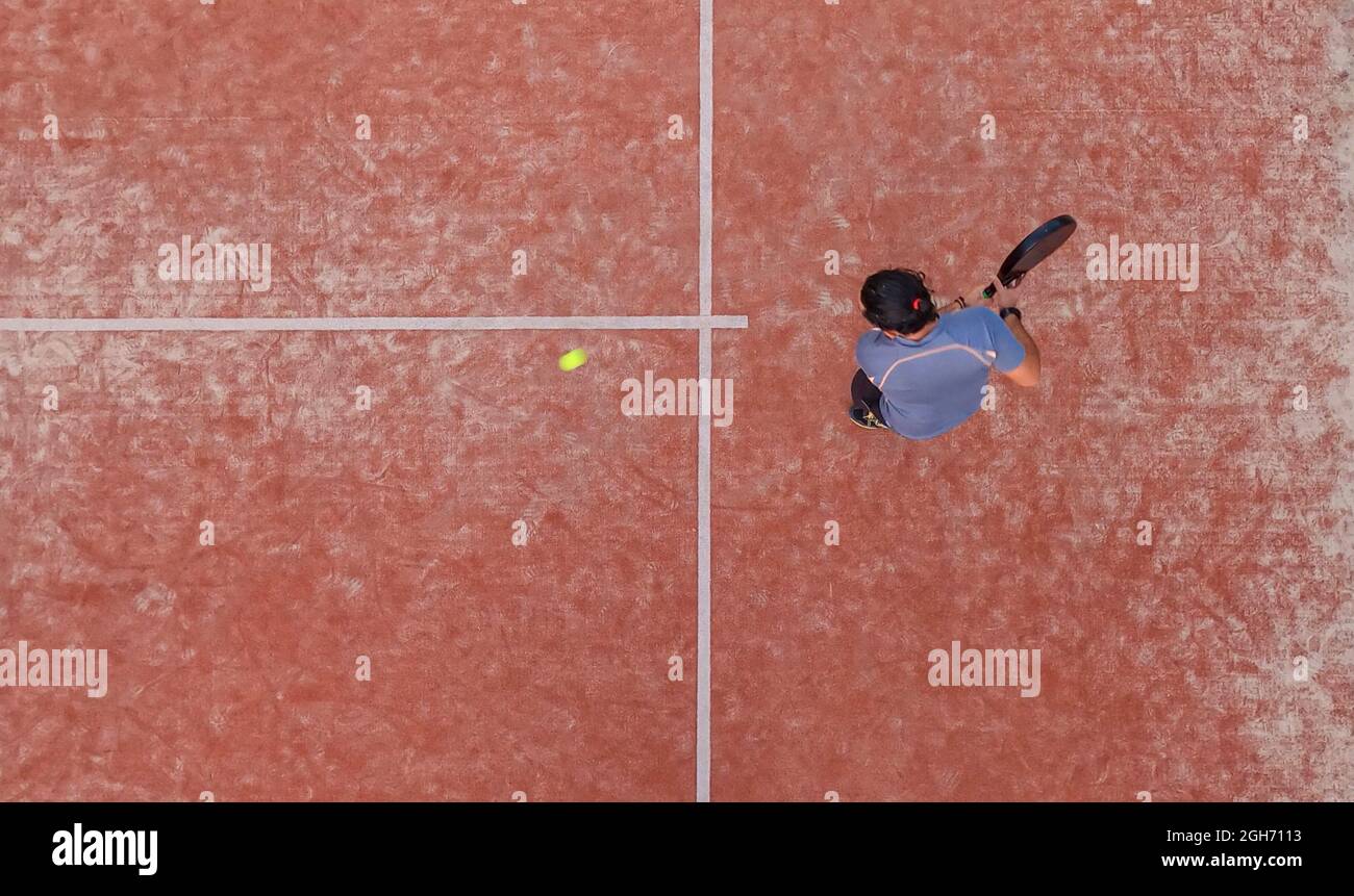 Vista superior de un jugador de padel que va a golpear la pelota con la raqueta durante un partido de padel o practicar en una cancha al aire libre Foto de stock