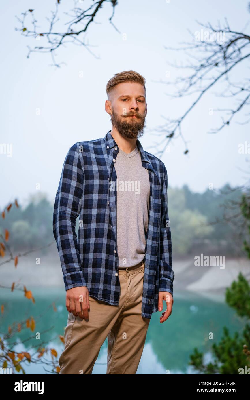 Joven hombre con barba de raza blanca camisa de cuadros viajando solo en el bosque de otoño y mirando el lado. Senderismo, viajes al aire libre, recreación y concepto de