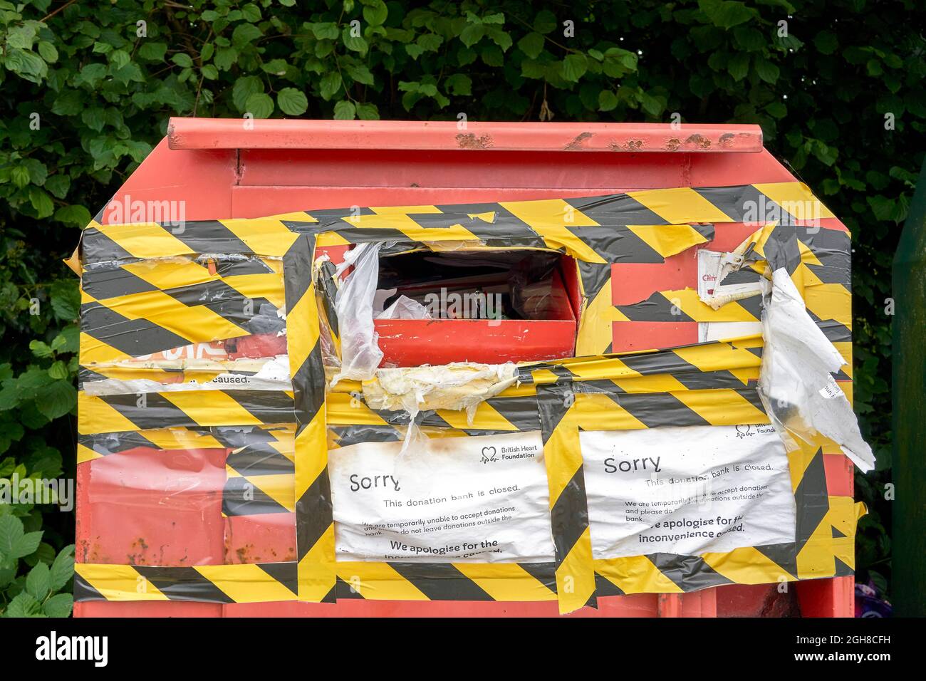 Papelera de reciclaje de beneficencia cerrada para donaciones y envuelta en cinta de advertencia de peligro negra y amarilla Foto de stock