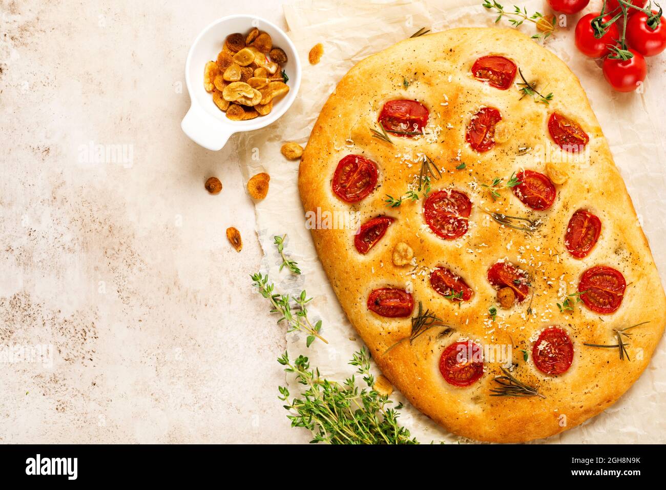 Pan italiano tradicional focaccia horneado con tomates cherry, parmesano y romero sobre fondo marrón claro. Vista superior Foto de stock