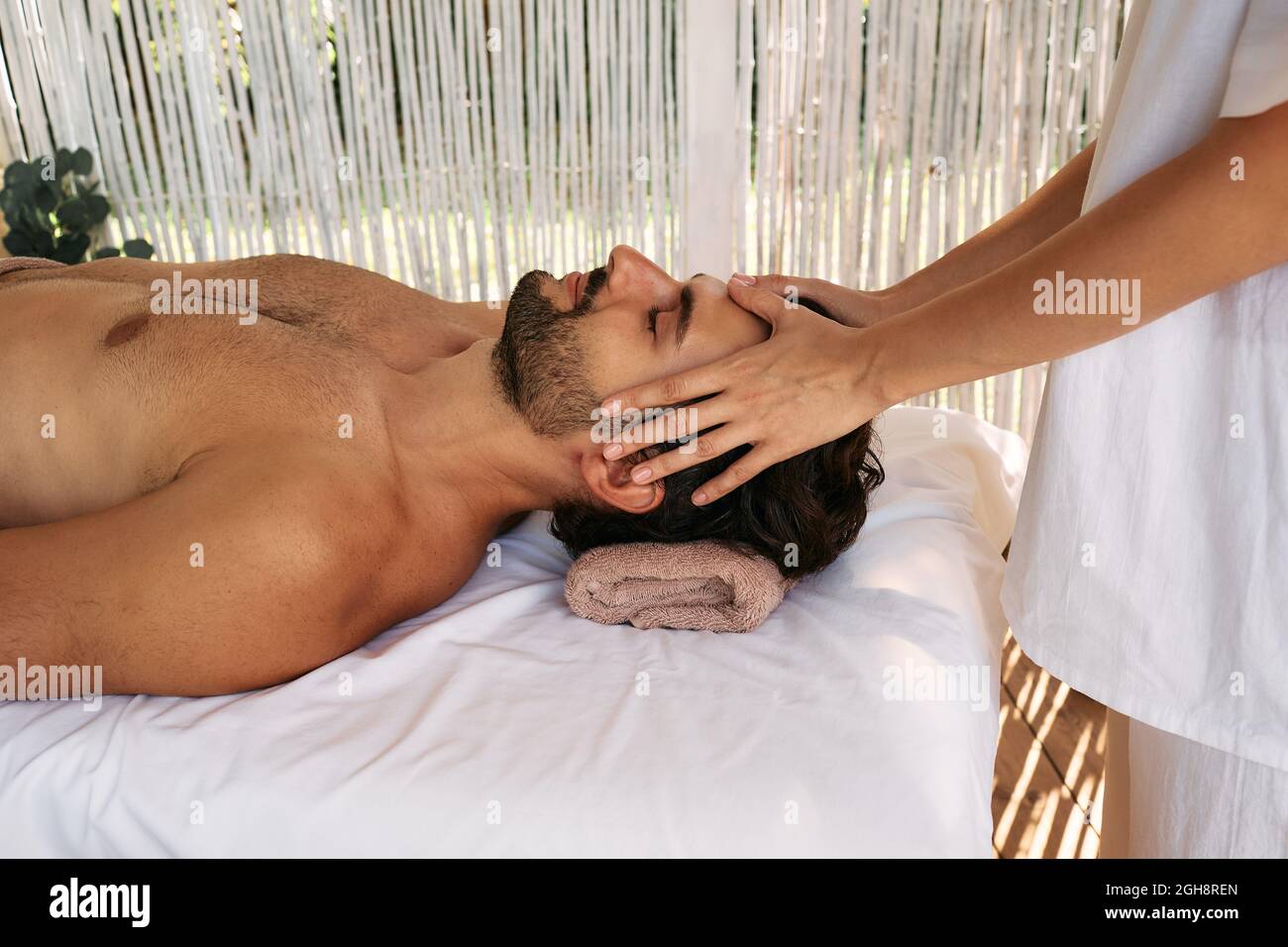 El hombre guapo recibe un masaje de cabeza y disfruta de un descanso en el spa. Masaje de cabeza antiestrés, primeros planos Foto de stock