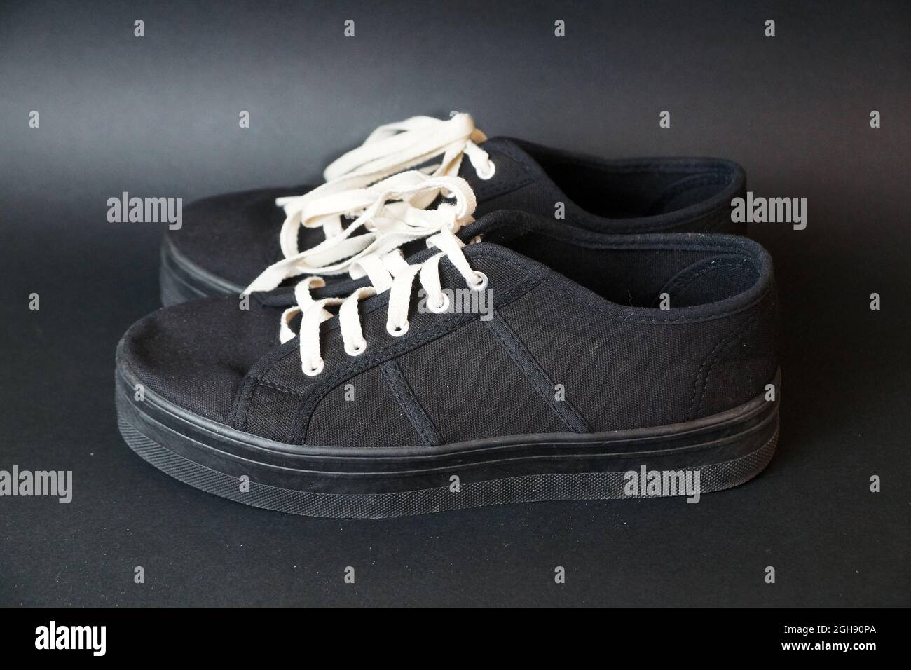sneakers negras con cordones blancos sobre fondo negro Fotografía de stock  - Alamy
