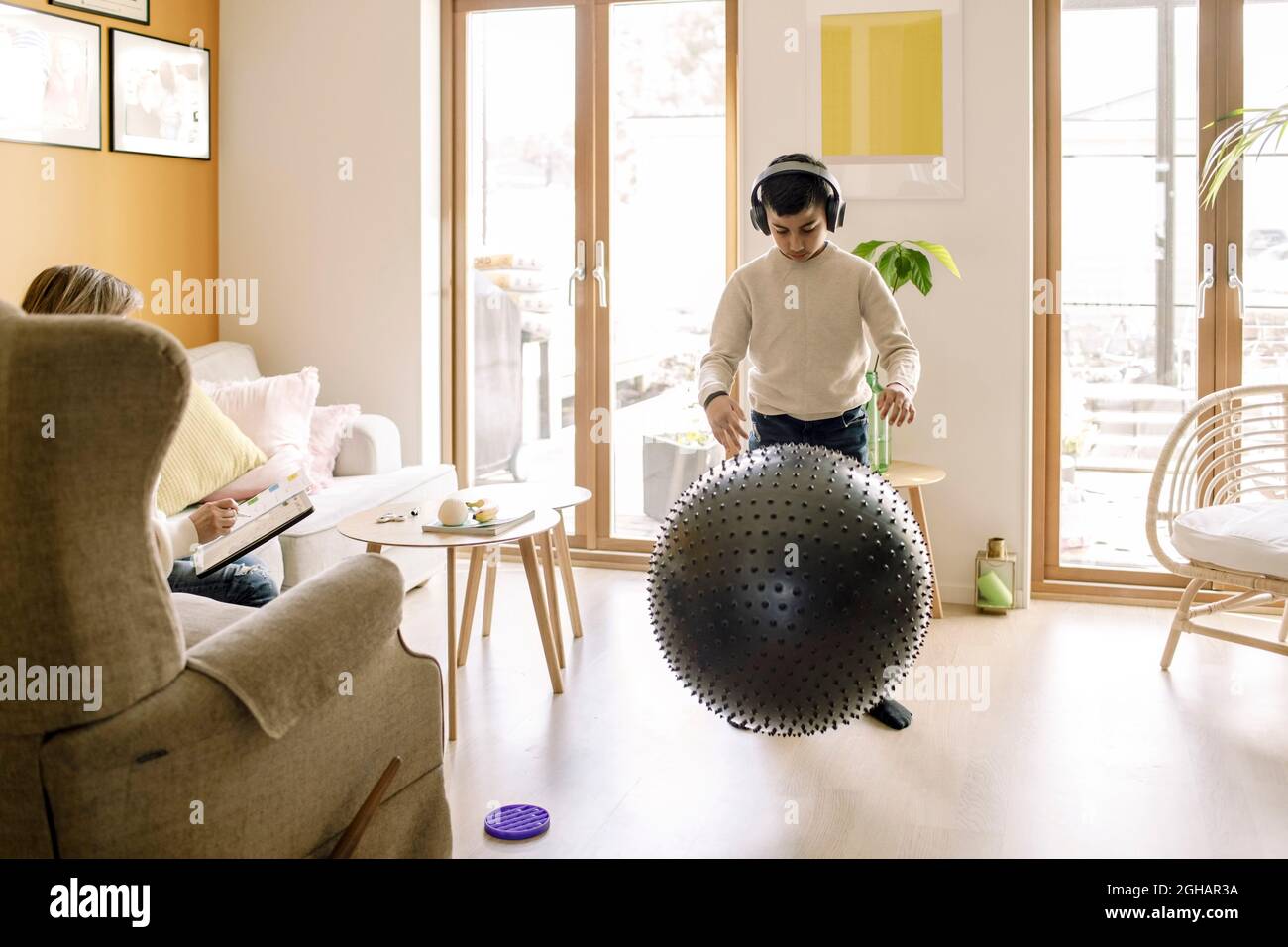 Niño pre-adolescente jugando con pelota de fitness en la sala de estar Foto de stock