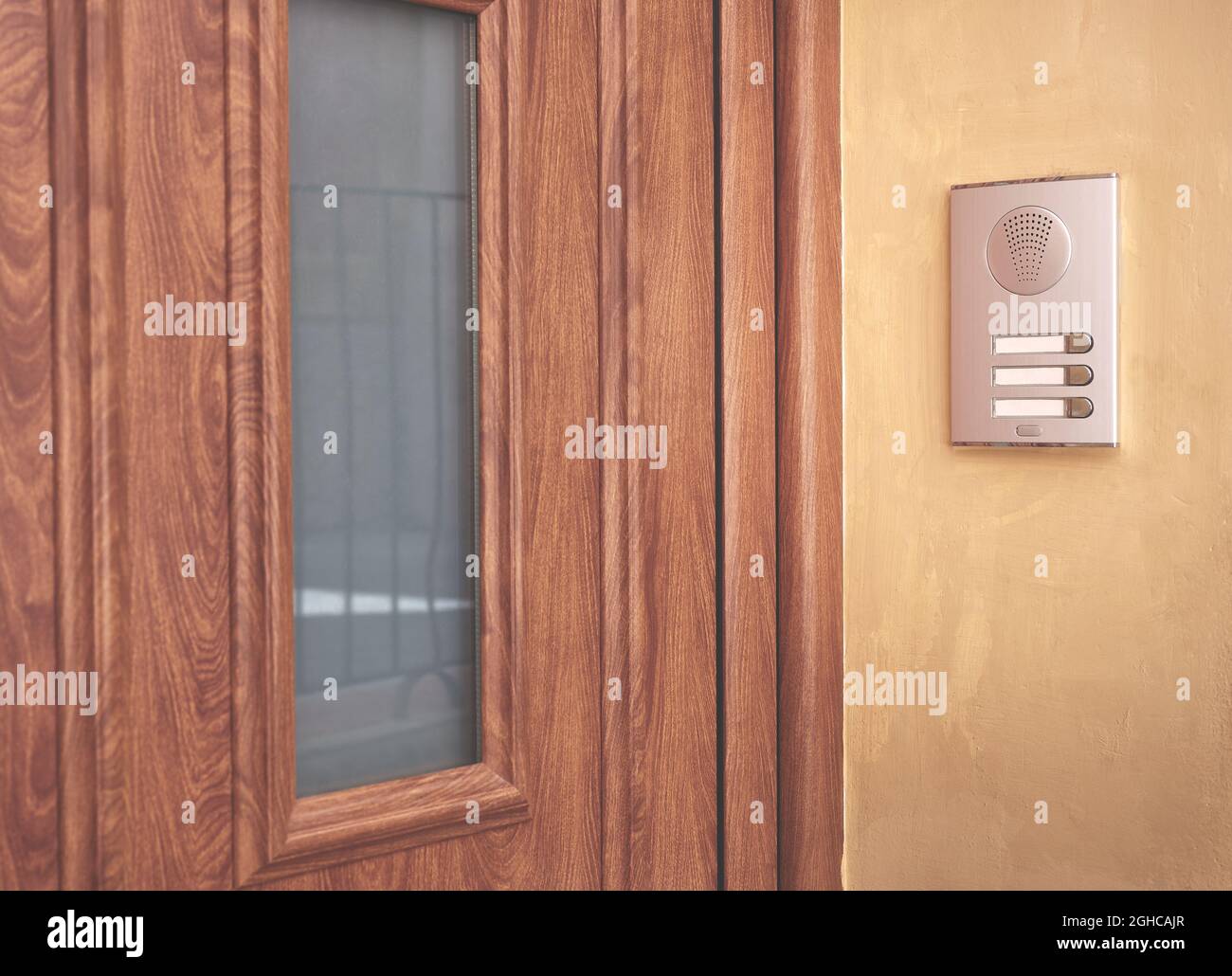 detalle de una puerta de entrada marrón con interfono en pared de estuco Foto de stock