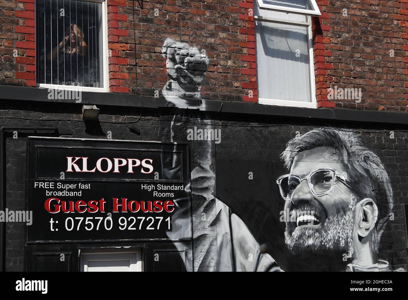 Una mujer mira desde una ventana encima de un mural del gerente de Liverpool Jurgen Klopp antes del partido de la Premier League contra el Arsenal en Anfield, Liverpool. Fecha de la foto: 24th de agosto de 2019. El crédito de la foto debe ser: Darren Staples/Sportimage via PA Images Foto de stock