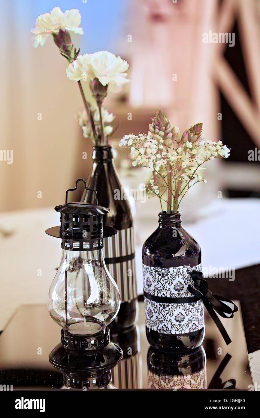 Cierre de botellas decoradas con flores y una linterna vintage en una TIL  con espejo en la mesa de recepción de bodas Fotografía de stock - Alamy