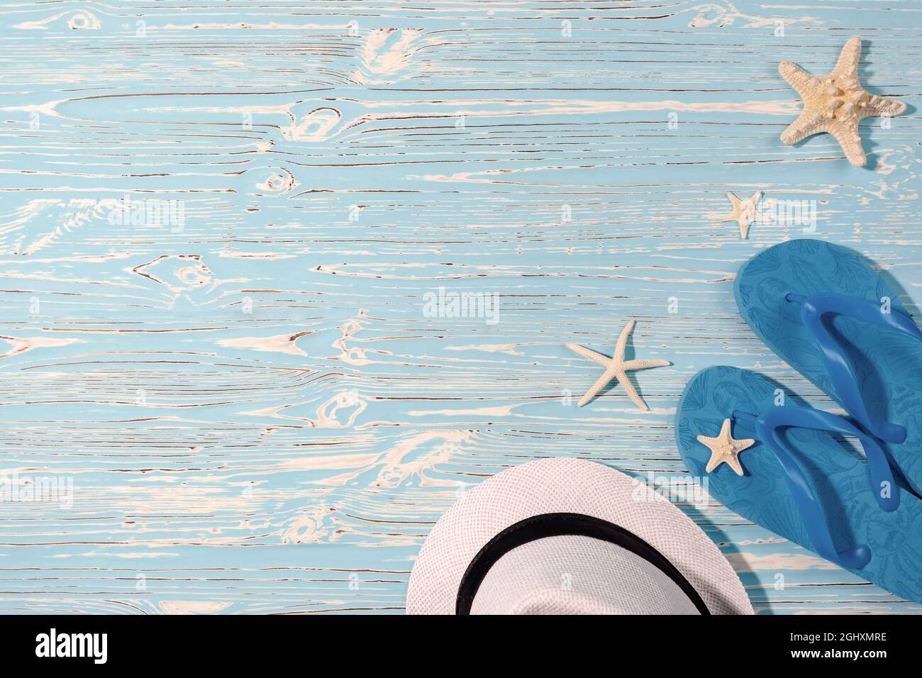 Sombrero de playa blanco, pez estrella, chanclas de goma azul sobre un  fondo de madera azul Fotografía de stock - Alamy