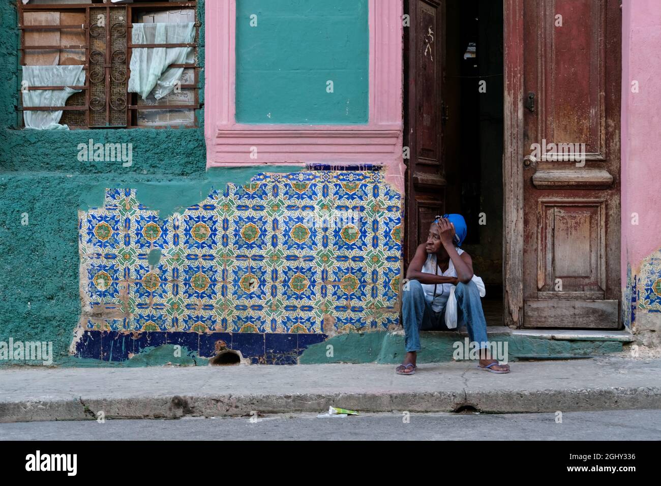 Una mujer se sienta junto al camino en La Habana, Cuba. Foto de stock