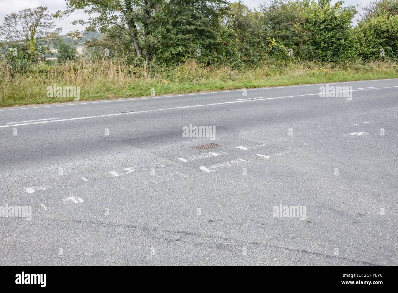 Las marcas blancas de la carretera en el cruce en T de una carretera del país A. Para la seguridad vial, la metáfora de desvanecimiento, difícil de ver. Foto de stock