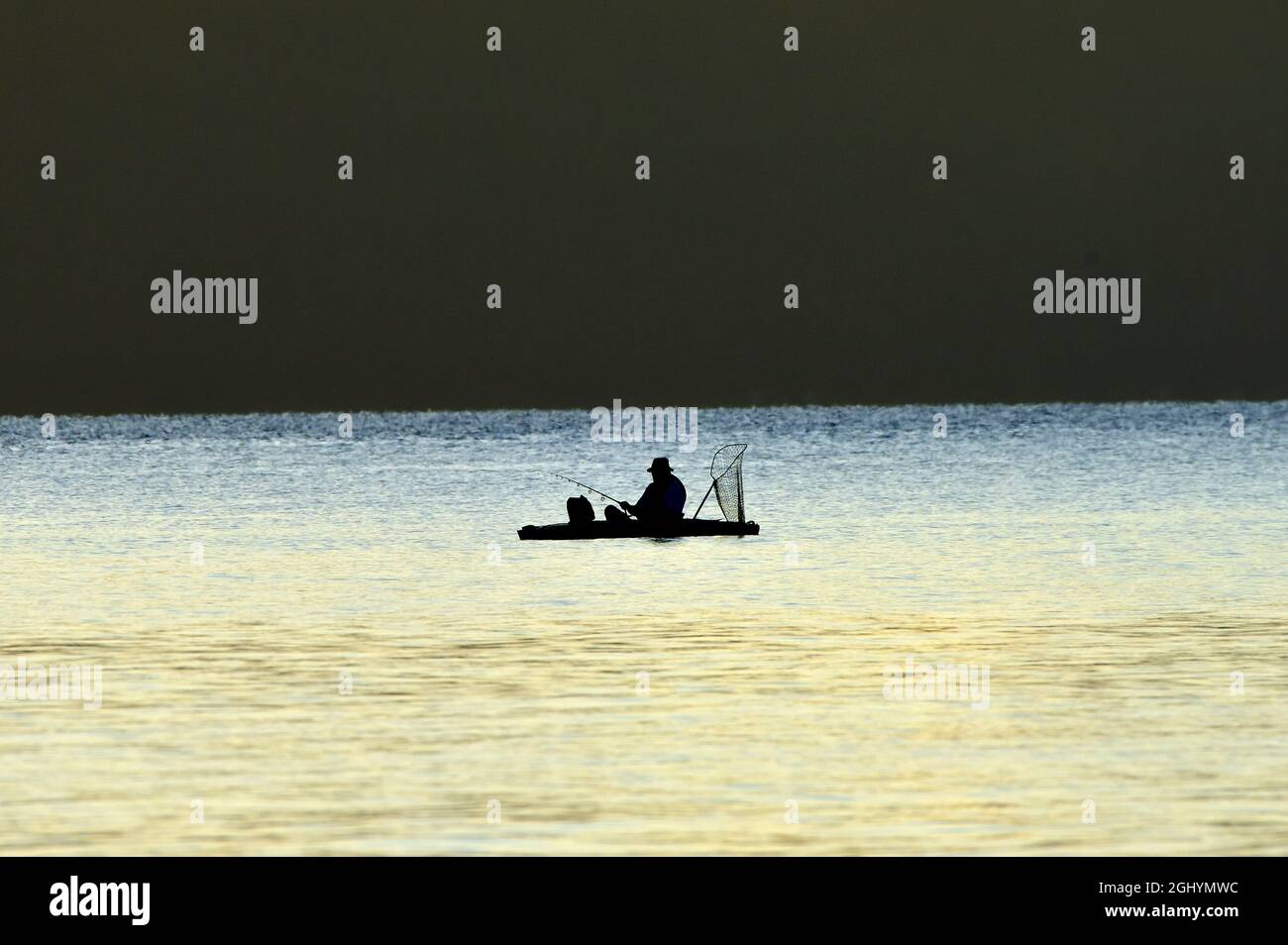 Una silueta de un hombre pescando desde un barco de goma en el canal Stewart en la costa de la isla de Vancouver British Columbia Canadá. Foto de stock