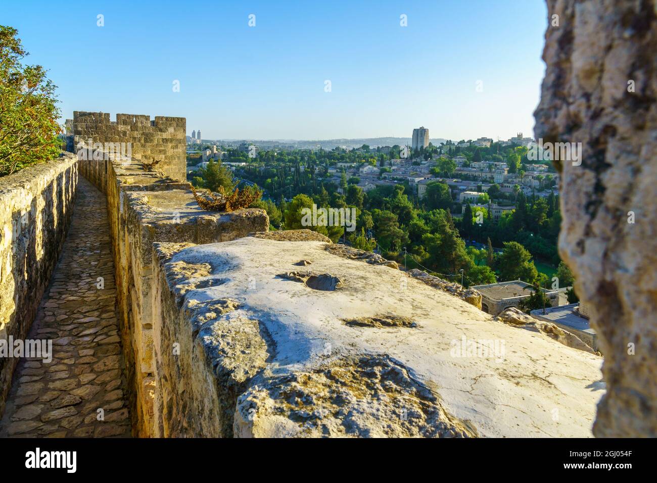 Vista de la caminata de las murallas, sobre las antiguas murallas de la ciudad, y el barrio Yemin Moshe en la nueva ciudad, con su molino de viento, en Jerusalén, Israel Foto de stock