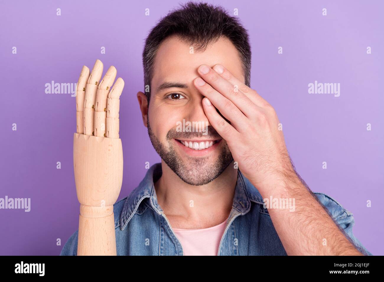Foto del joven feliz sonrisa positiva ojo cercano mano mostrar prótesis amputado aislado sobre fondo de color púrpura Foto de stock