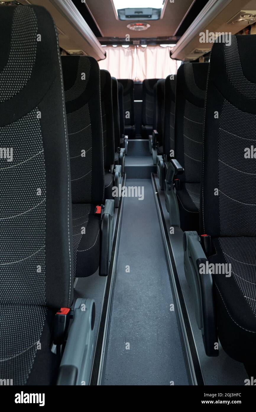 Interior del pasillo vacío del autobús limpio con filas de asientos de tela negra Foto de stock