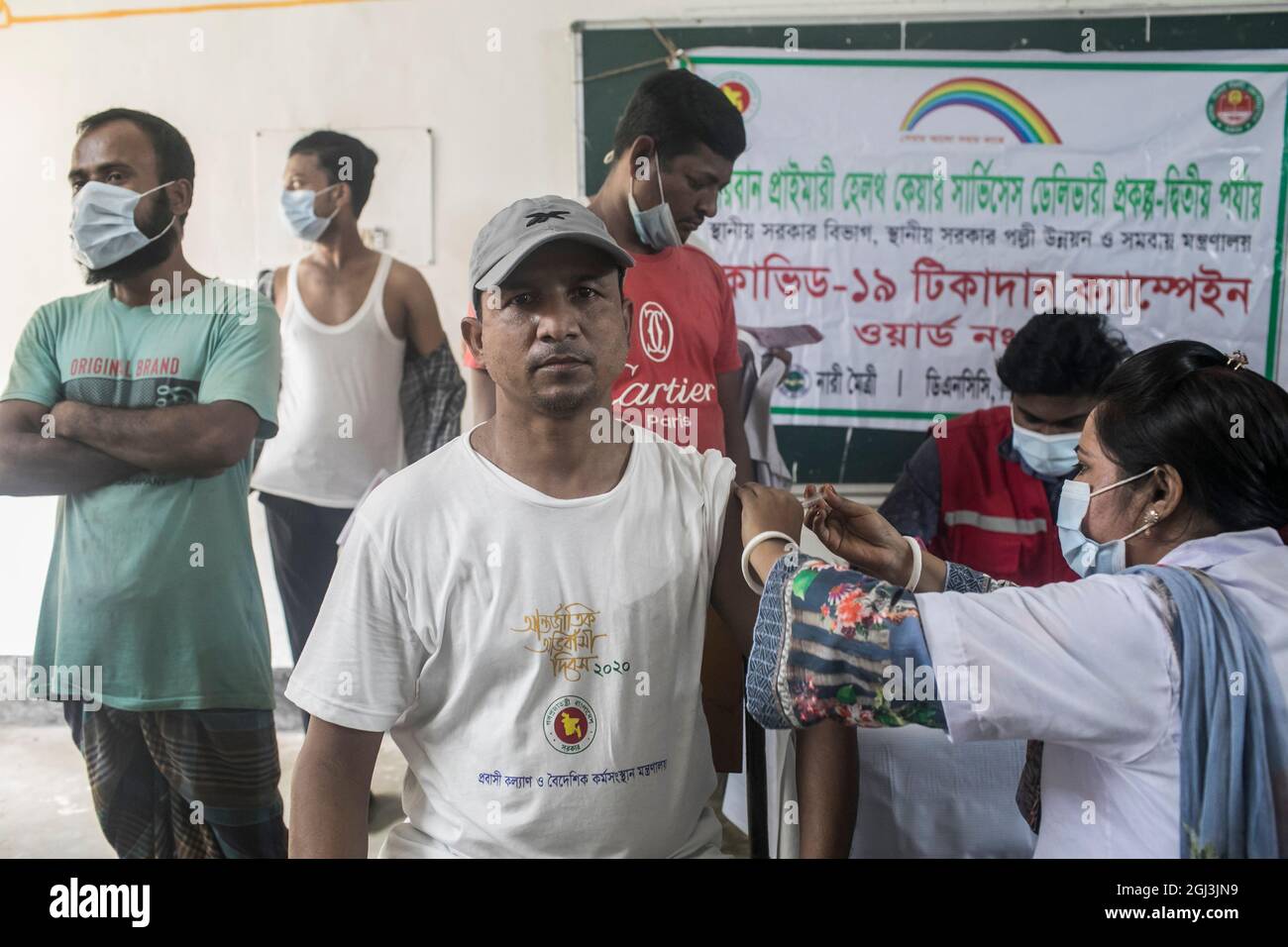 Un trabajador de salud administra una dosis de la vacuna Moderna COVID19 a un hombre durante una campaña de vacunación en un centro de vacunación en Dhaka.Los residentes de Bangladesh se reúnen en gran número en la Escuela Primaria del Gobierno Mohammadpur, un centro de vacunación designado en Dhaka para recibir una dosis de vacunación Covid-19, Un segundo día en la campaña de vacunación masiva que comenzó el 7 de septiembre y terminará el 12th. (Foto de Sazzad Hossain / SOPA Images/Sipa USA) Foto de stock