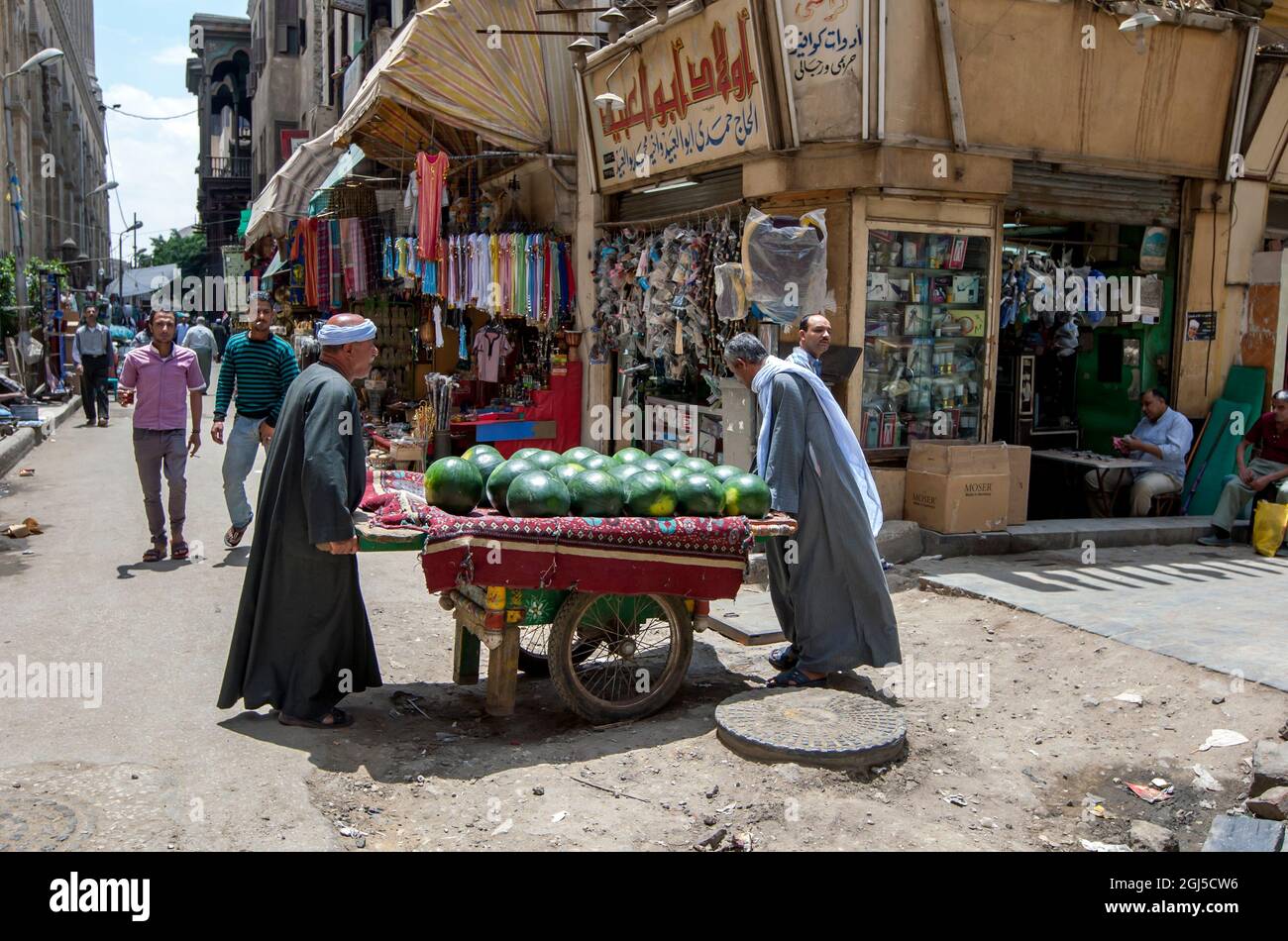 Los hombres transportan un carro cargado de sandías a través de una calle en el Bazar Khan el-Khalili en El Cairo, Egipto. Foto de stock