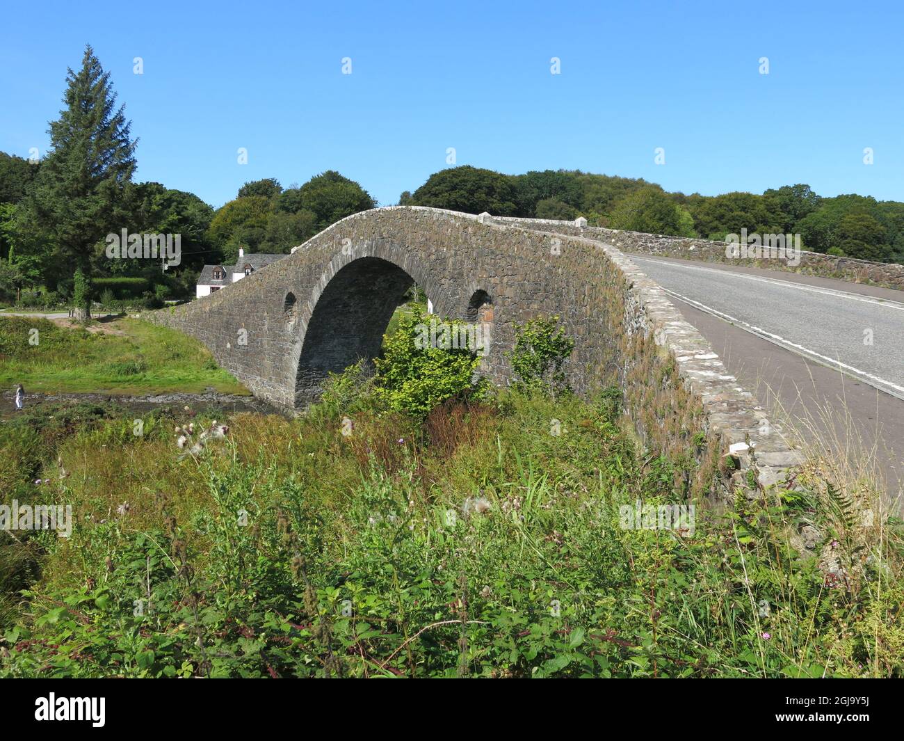 El puente Clachan, de arco sencillo y con respaldo de joroba, se conoce como el puente sobre el Atlántico, que conecta el continente escocés con la isla de Seil. Foto de stock