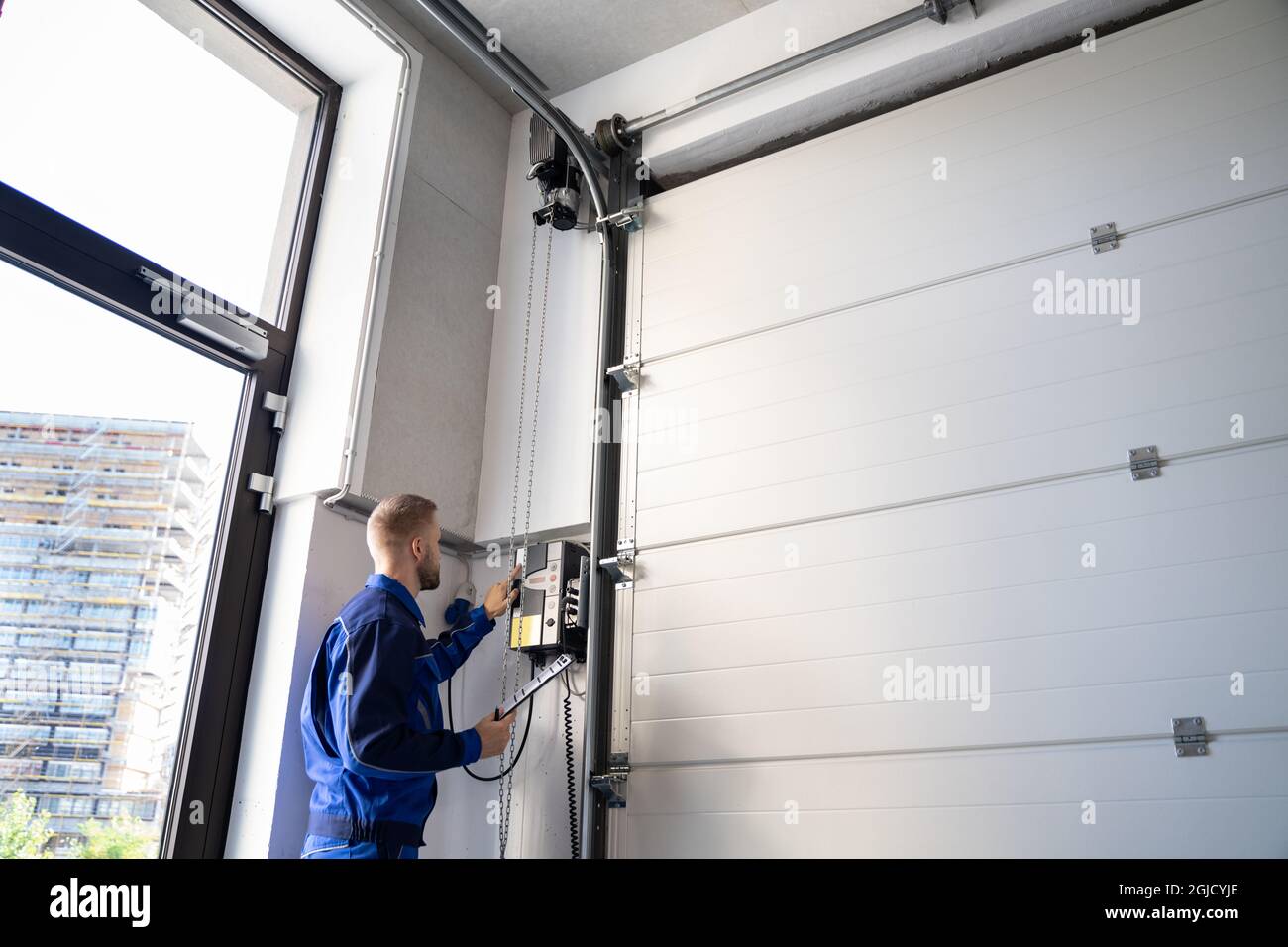 Instalación y reparación de puertas de garaje en casa. Hombre contratista  en casa Fotografía de stock - Alamy