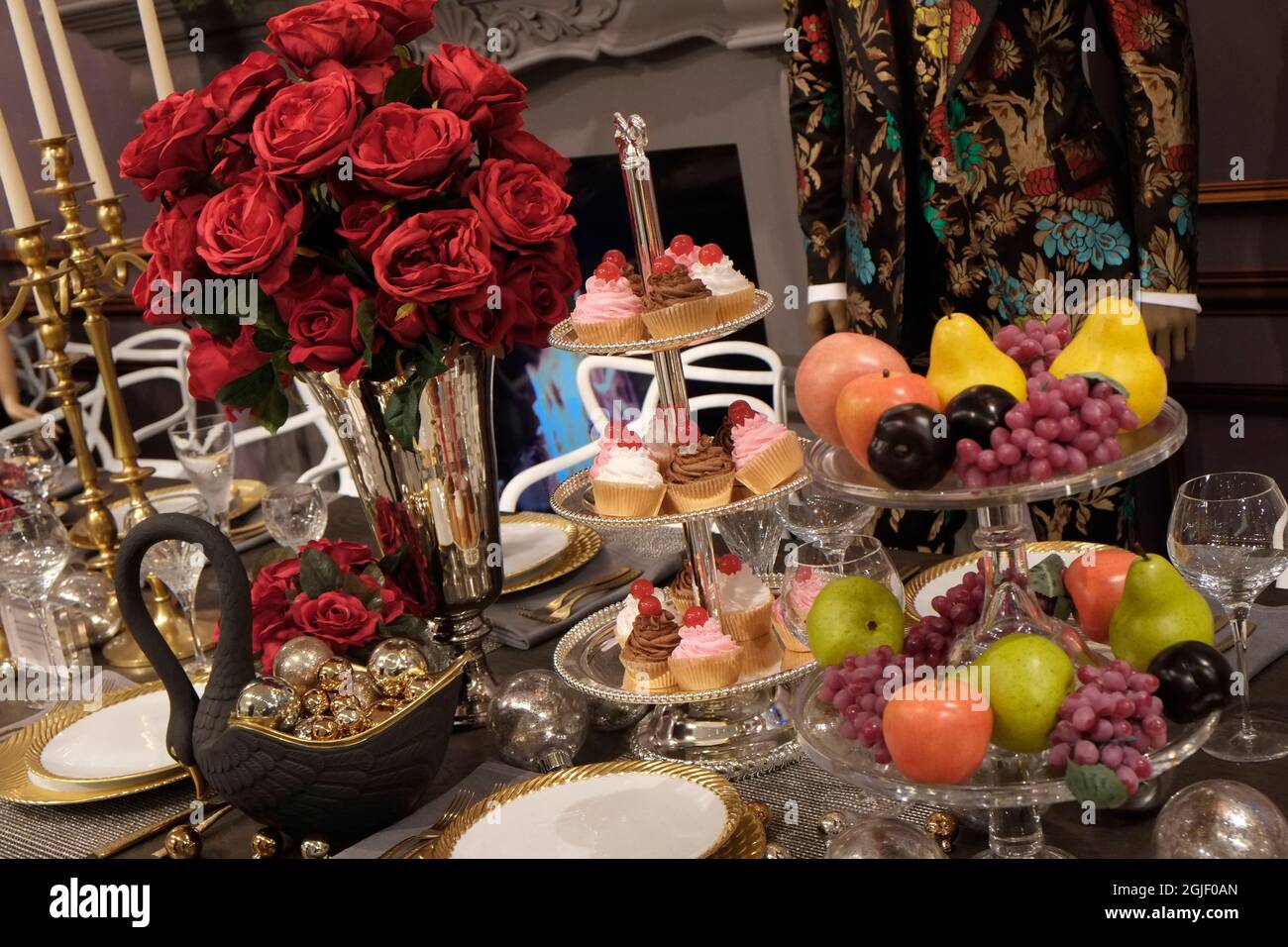 Exposición de mesa de vacaciones con frutas y dulces y jarrón de rosas. Foto de stock