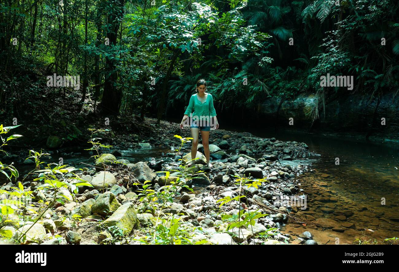 Mujer caminando sobre piedras en el bosque junto a un río en Bofete - SP Brasil Foto de stock