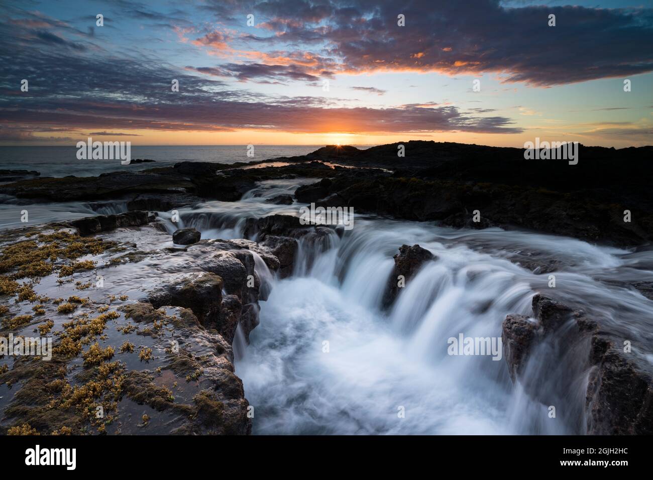 La oleada de olas drena desde una costa de roca de lava al atardecer, Keahole, North Kona, Hawaii Island ( The Big Island ), Hawaii, EE.UU. ( Central Pacific Ocean Foto de stock