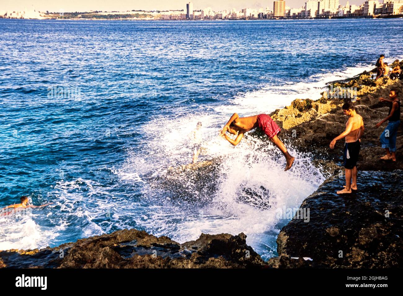 Jóvenes cubanos buceando en el mar sobre rocas en el Malecón, La Habana, Cuba Foto de stock