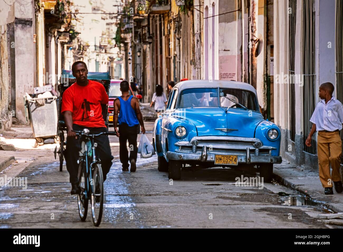 El coche clásico americano de la era de los años cincuenta, los peatones y el bicilo en la calle, La Habana, Cuba Foto de stock