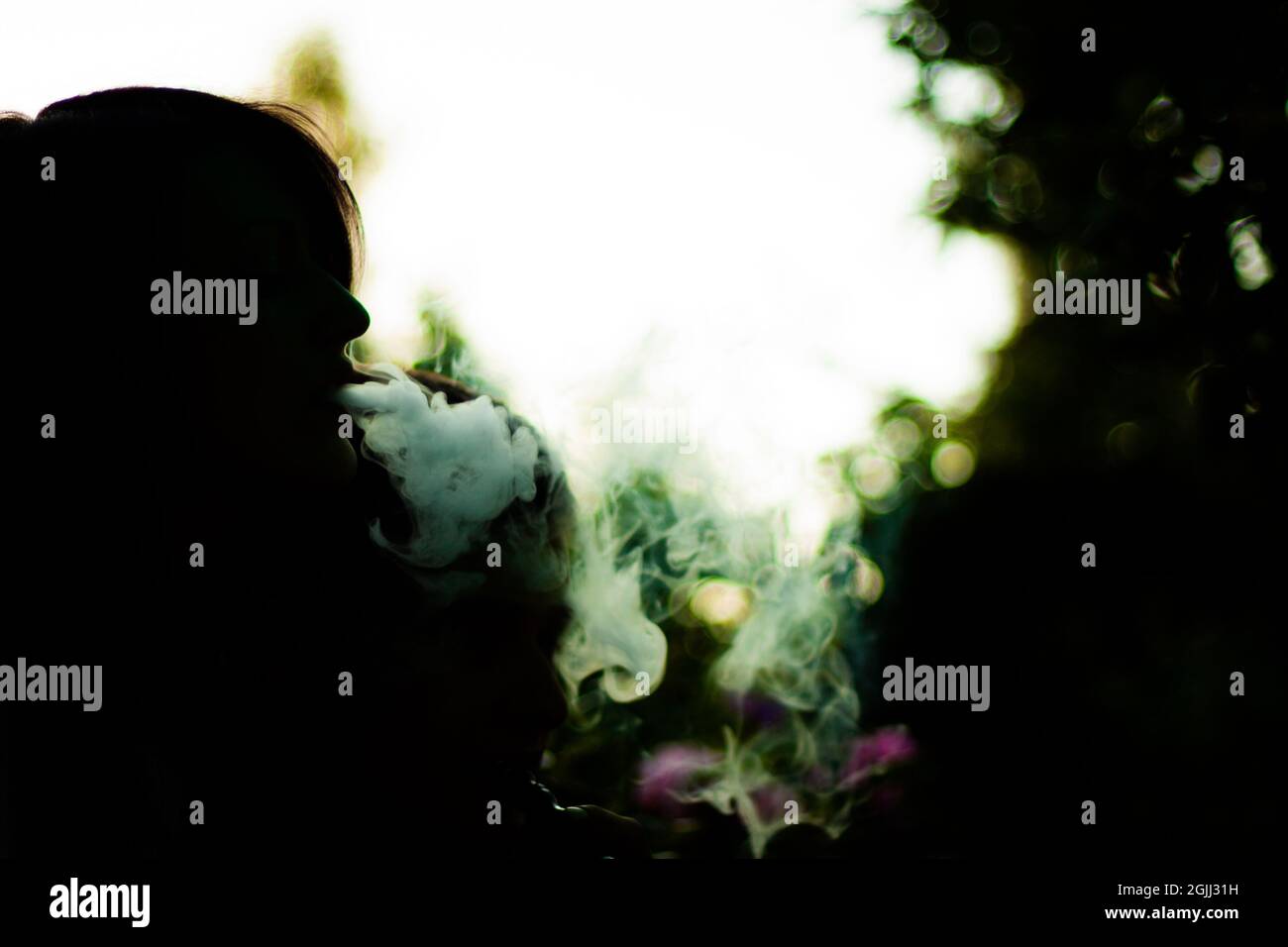 Silueta de una persona fumando narguile y soplando el humo sobre un